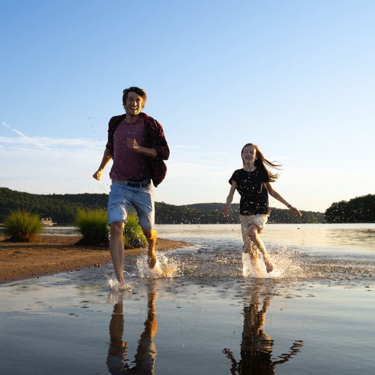 Père et fille courant à la plage.