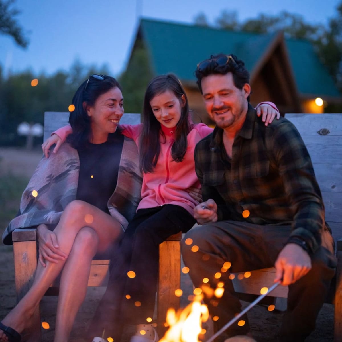 Famille heureuse à un feu de camp en soirée.