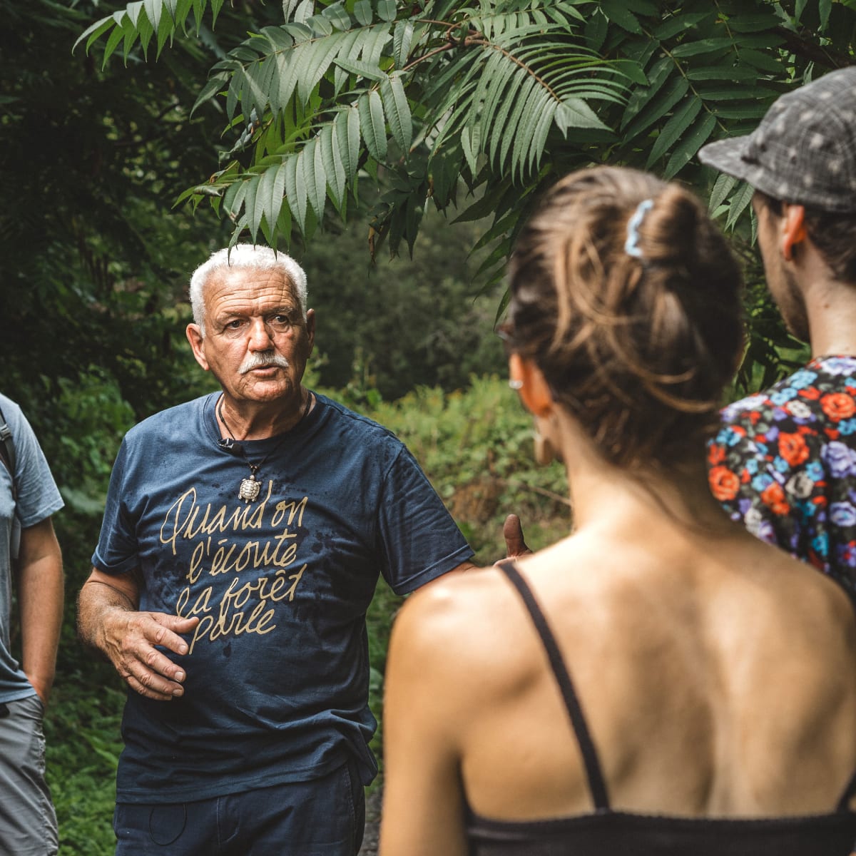 Groupe de personnes autour d'un aîné en forêt