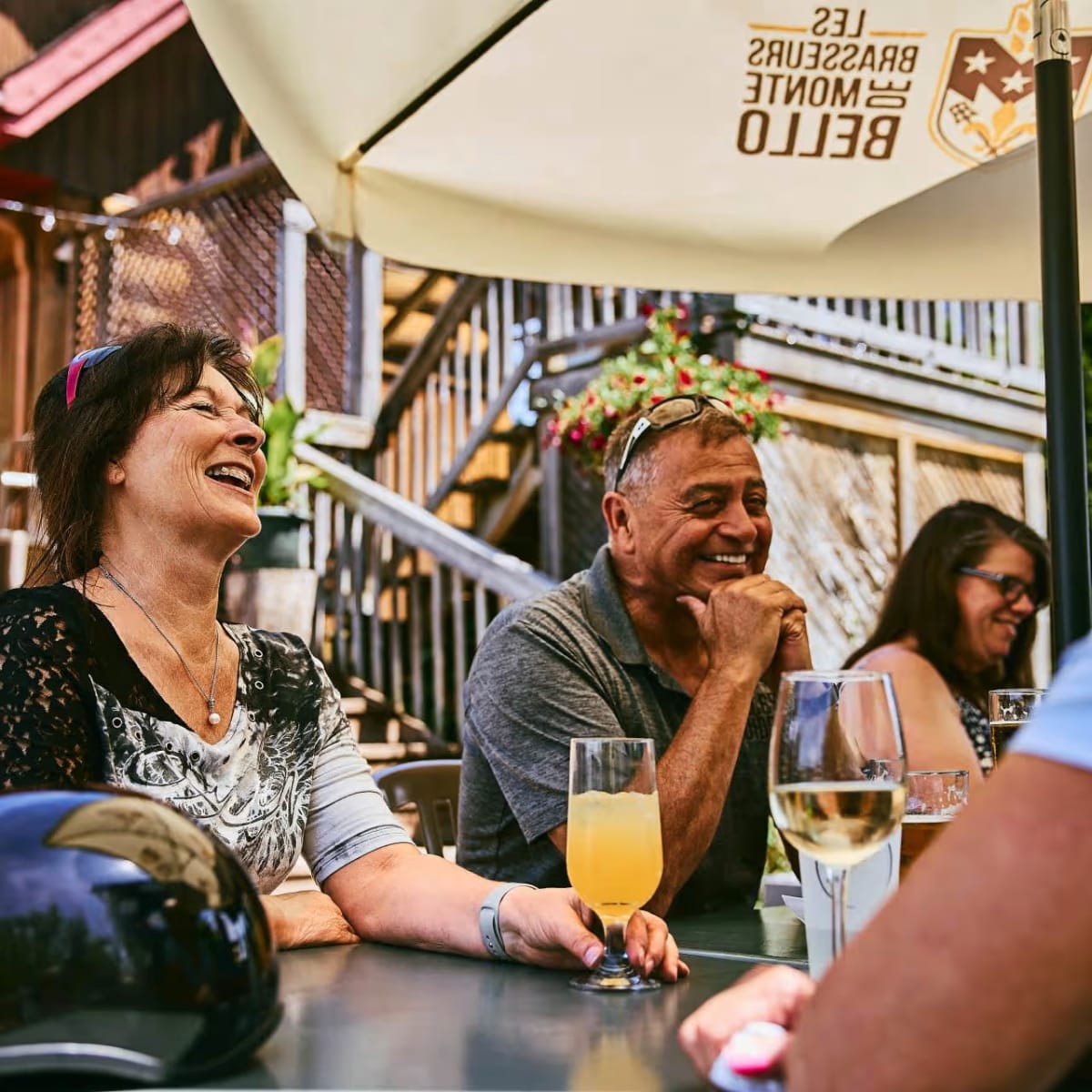 Personnes attablées sur une terrasse avec parasols en train de prendre un verre.