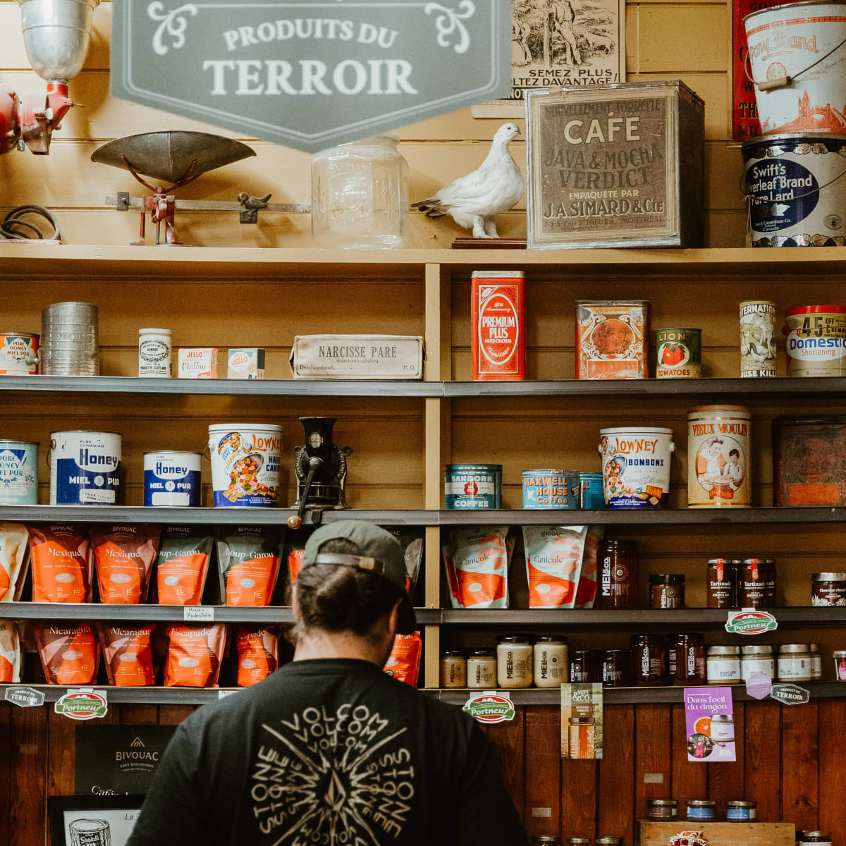 Homme devant un étalage de produits du terroir en boutique.