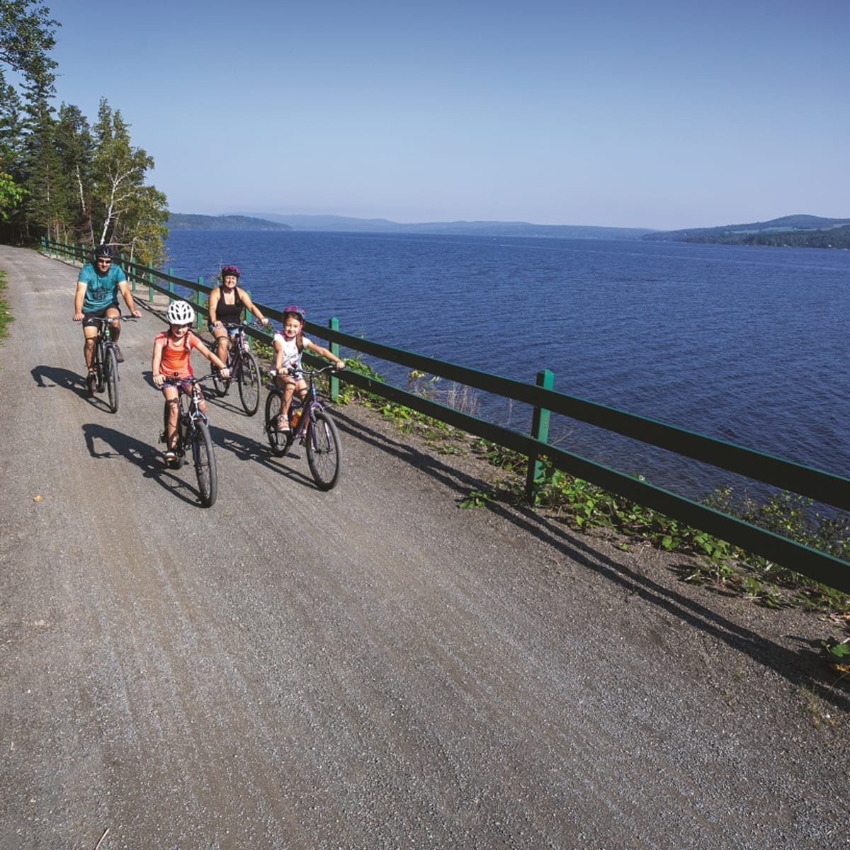 Famille de 4 personnes en vélo au bord du lac.