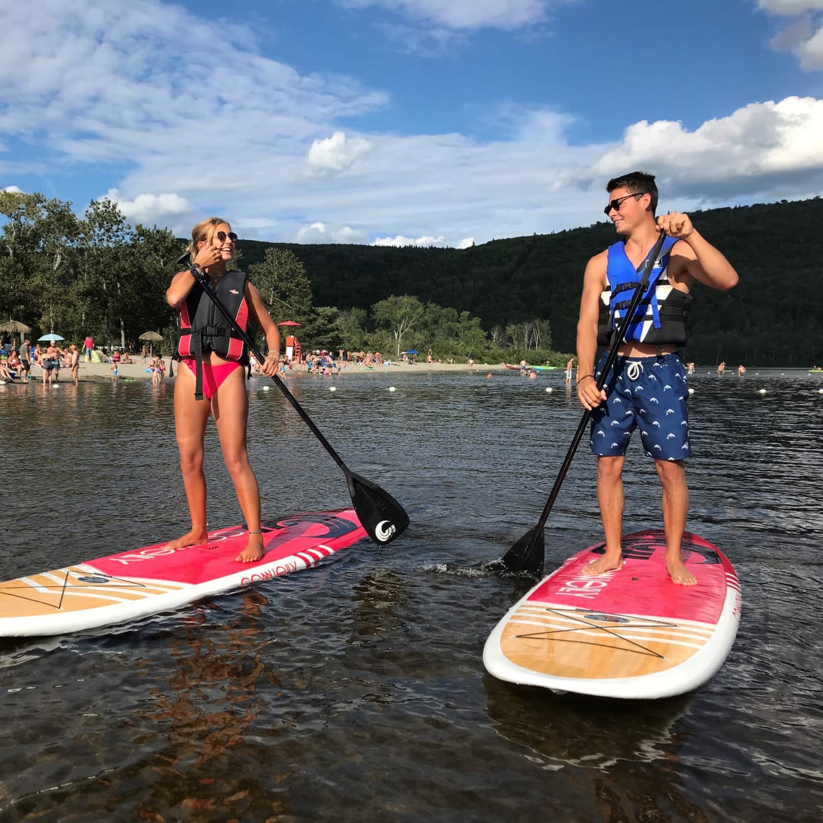 Jeune femme et jeune homme en planche à pagaie sur un lac.