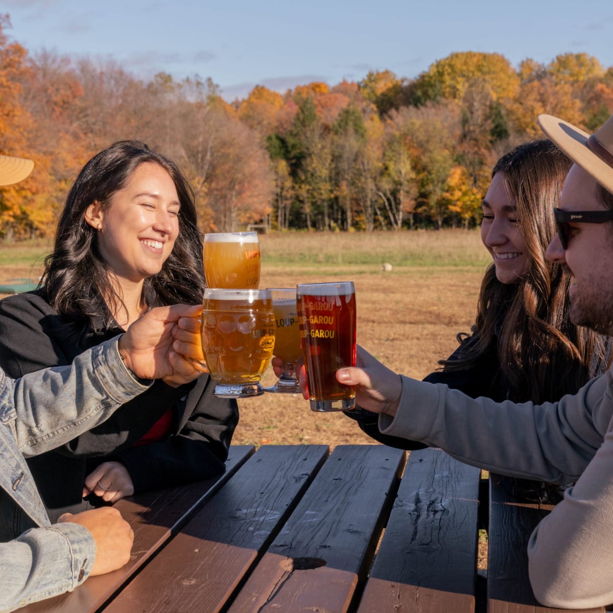 Toast de bières entre amis sur une table extérieure à l'automne.