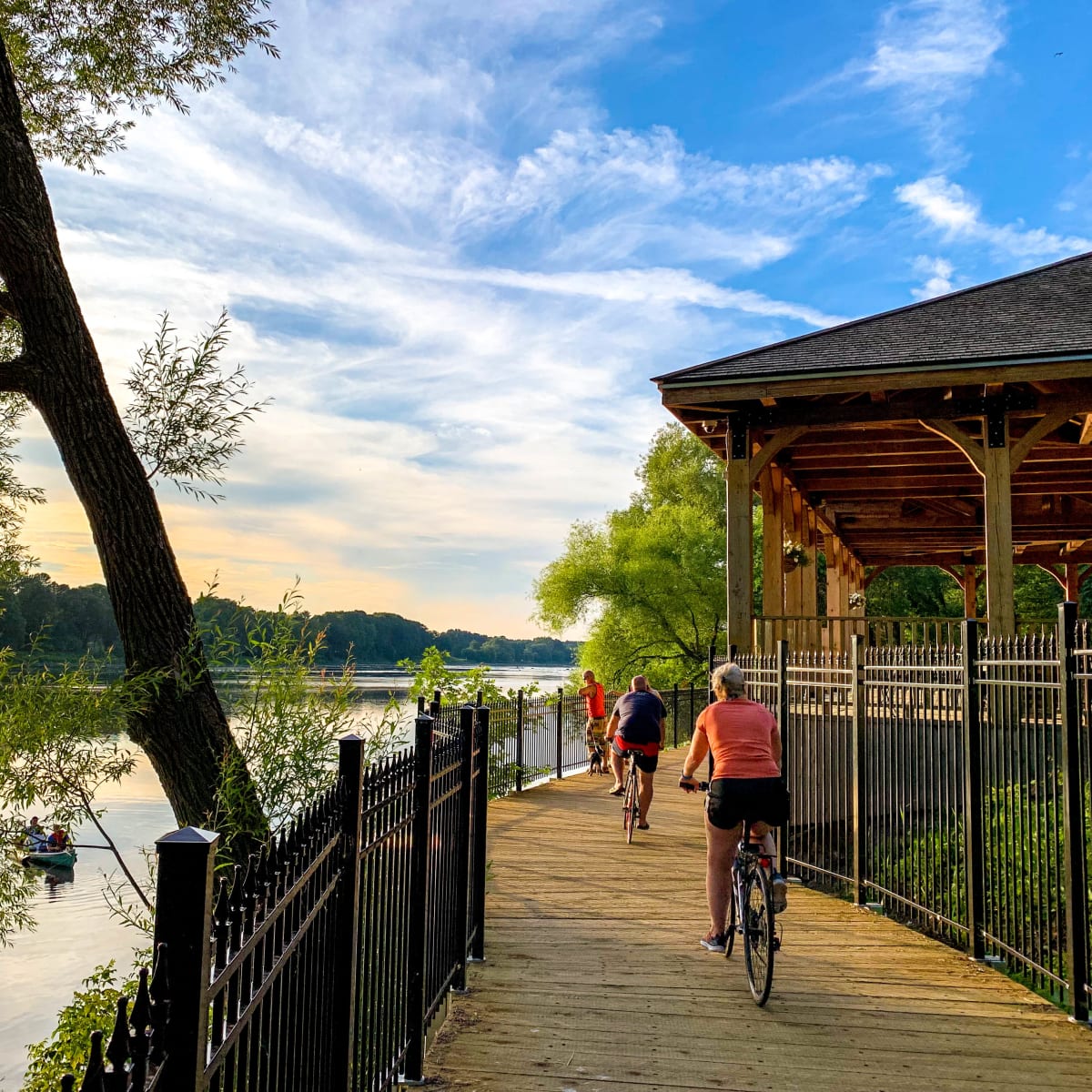 A few cyclists on a waterside bike path.