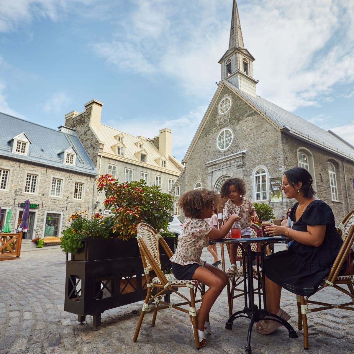 Family sitting at a table on Place Royale in Québec City. 