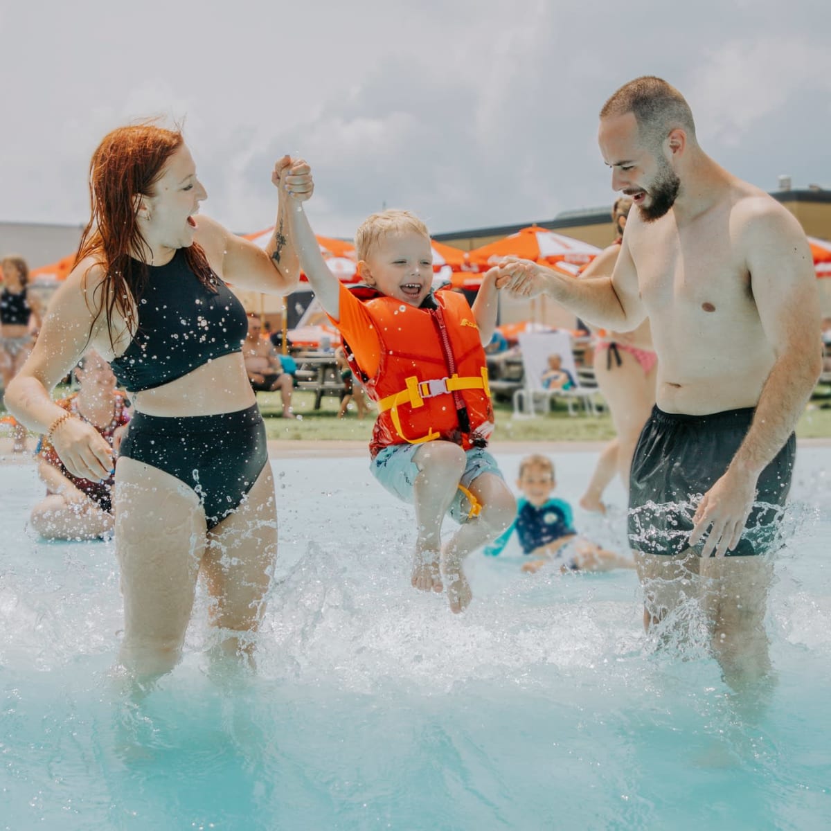 Mère, père et enfant dans la piscine à vagues.