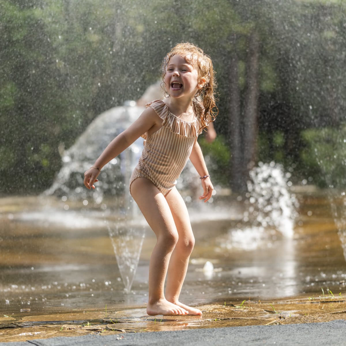 A little girl playing in the water games at the Zoo sauvage de Saint-Félicien.