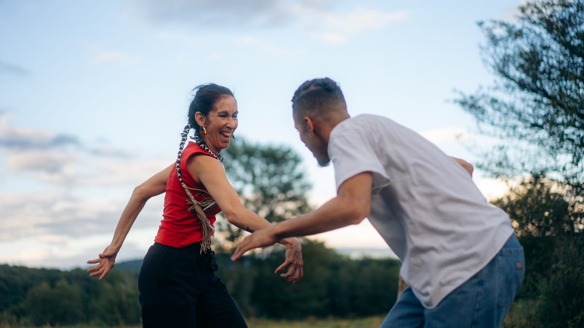 Une femme autochtone et un homme dancent en nature et s'amusent