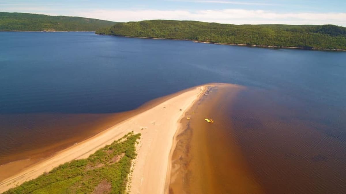 Plage sablonneuse s'étirant dans un lac.