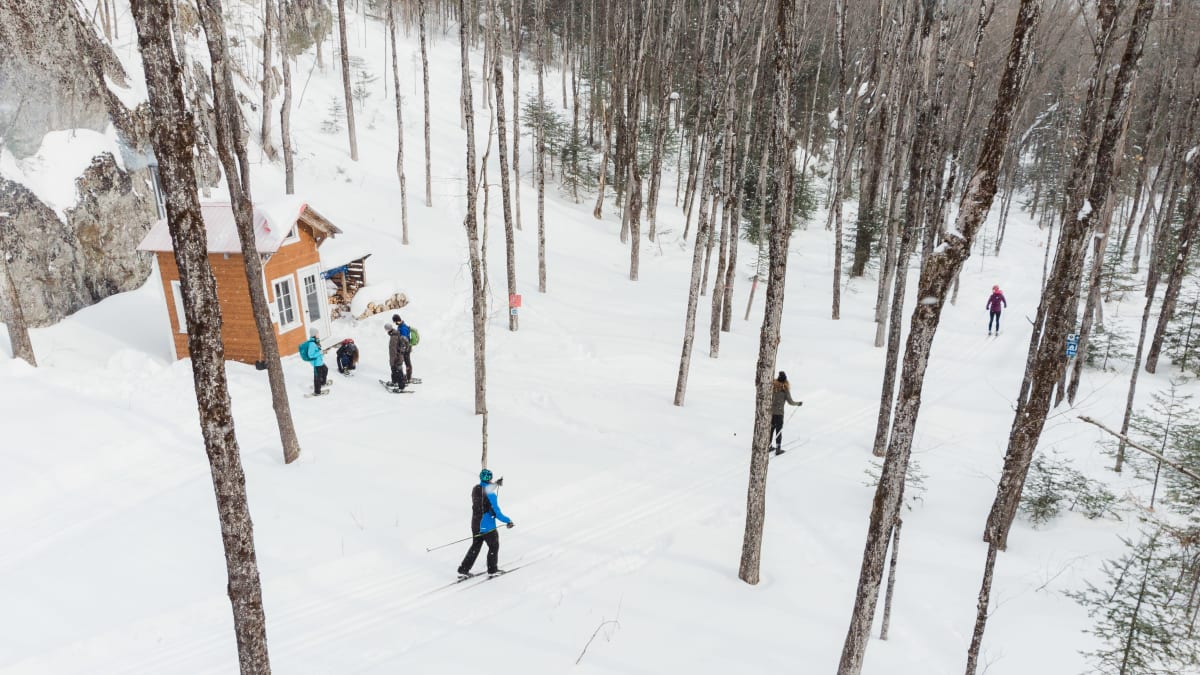 Raquetteurs et fondeurs près d'un relais au bord d'une piste enneigée au Club sportif des Appalaches.