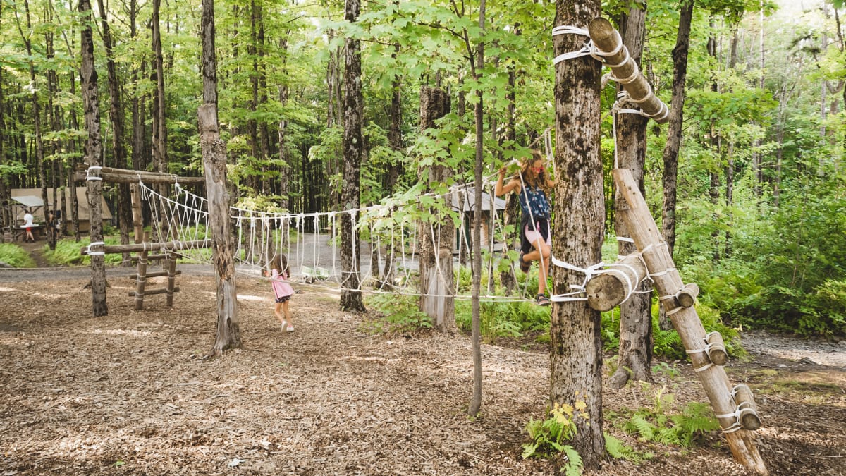 Kids on an obstacle course in the woods at Huttopia Sutton.