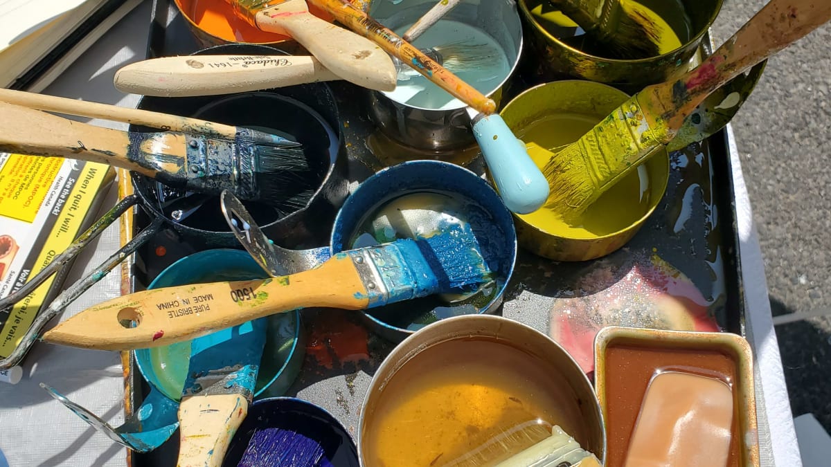 Plusieurs pots de peinture ouverts avec des pinceaux. 