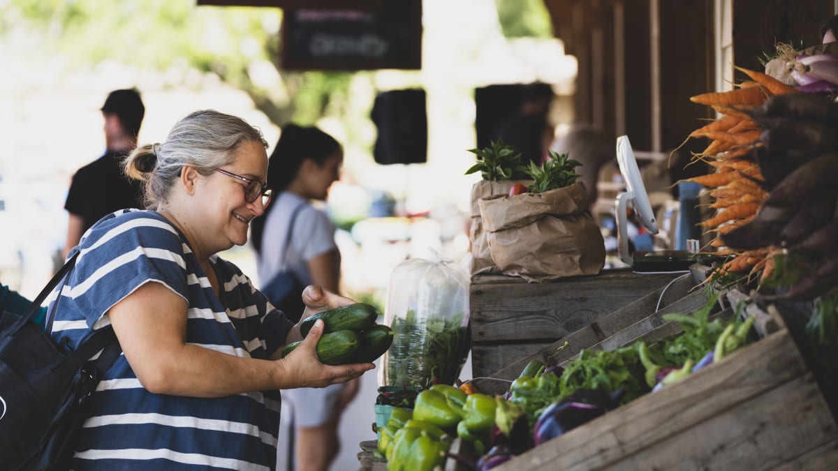 Woman at a farmer's market buying vegetables.