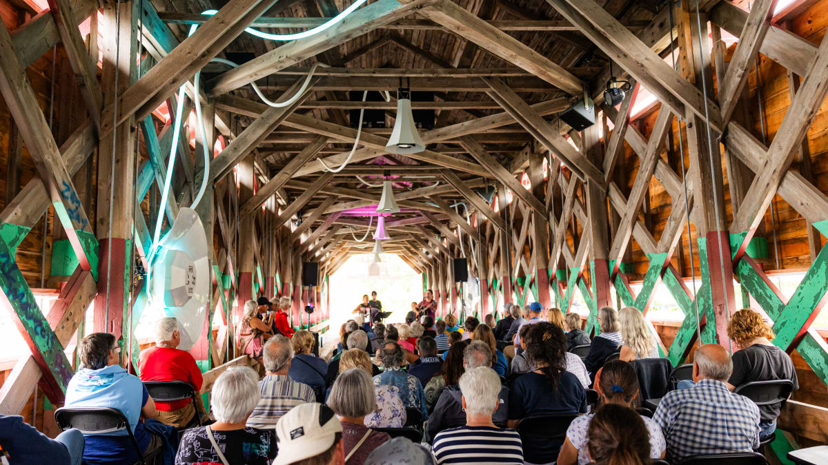 Foule assise dans une grange aménagée pour un spectacle.