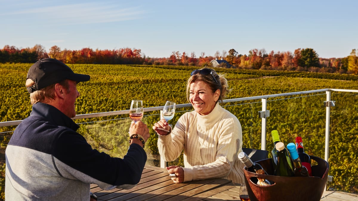 Couple outdoors in the fall sipping a glass of wine at Vignoble de l'Orpailleur.