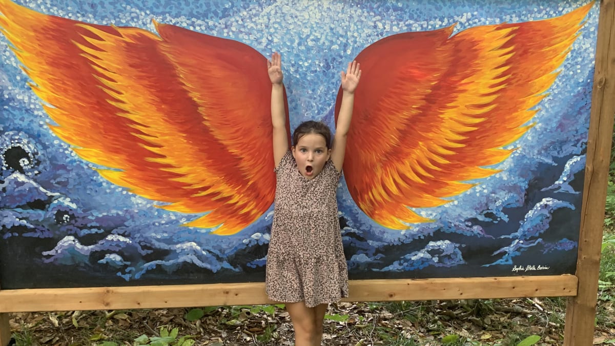 Young girl striking a pose in front of drawn wings.