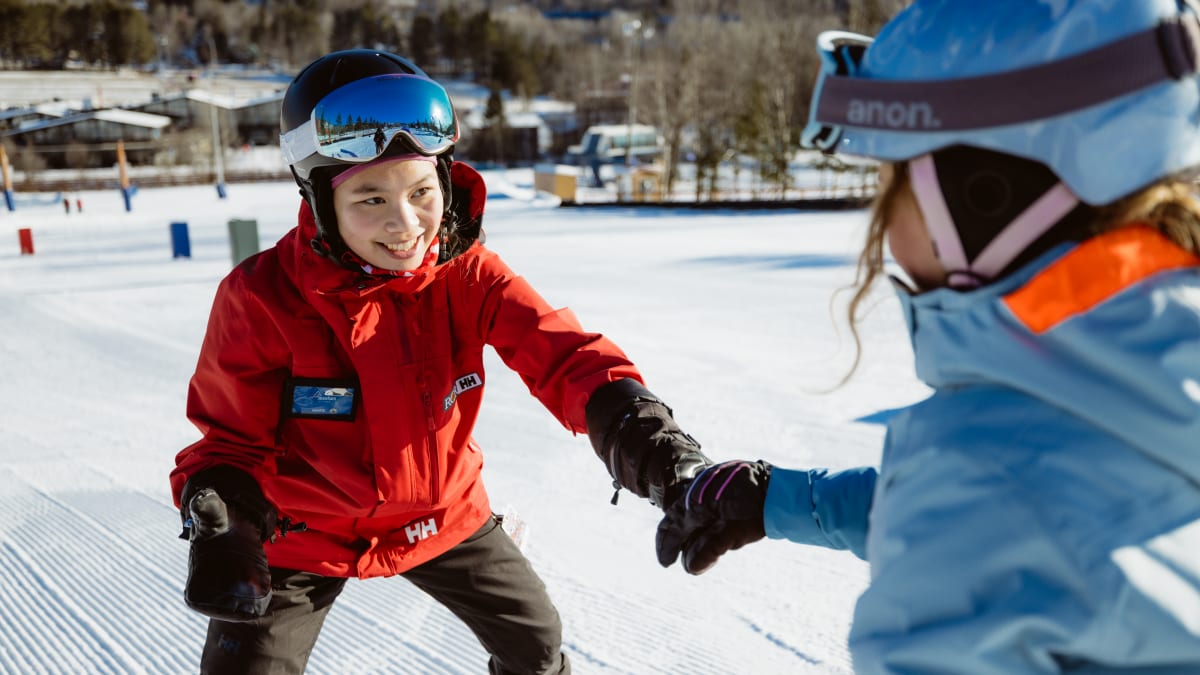 Smiling ski instructor with a trainee on the slopes.