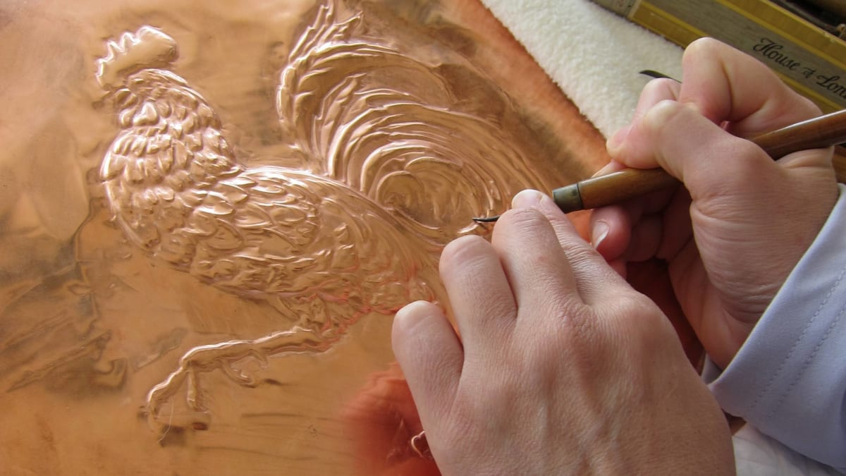 Artist embossing a sheet of copper