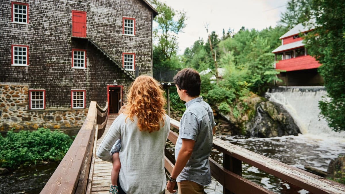 Jeune famille sur le pont devant le moulin à laine.
