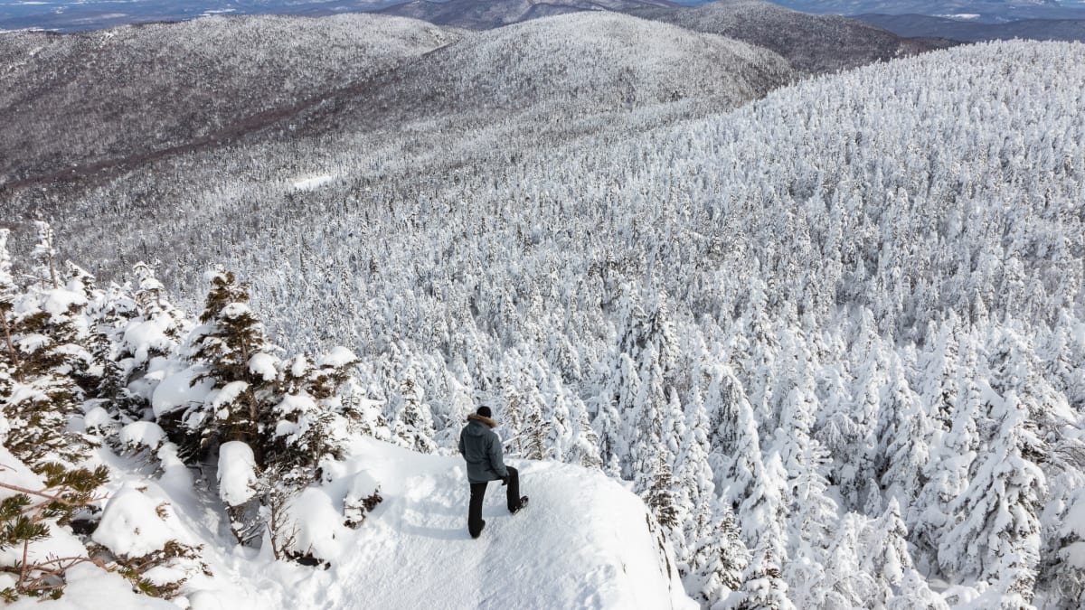 Homme perché au bord d'une falaise admirant la grandeur de la nature hivernale