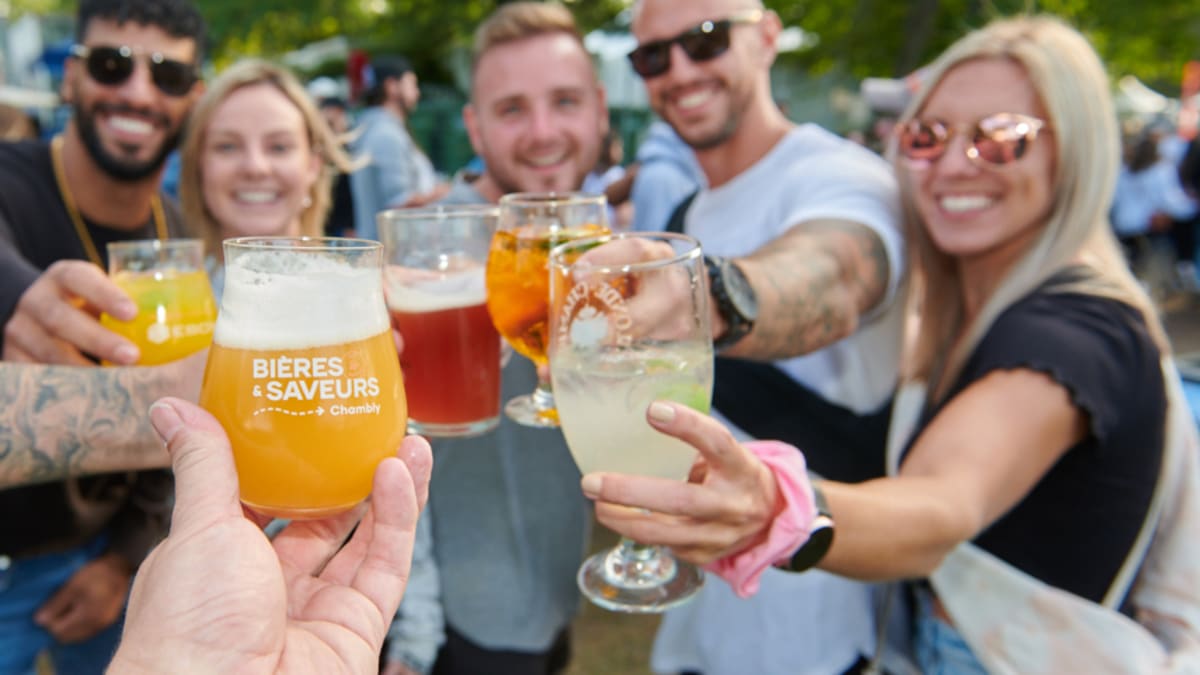 Groupe de personnes souriantes qui trinquent autour de leurs verres de bière.