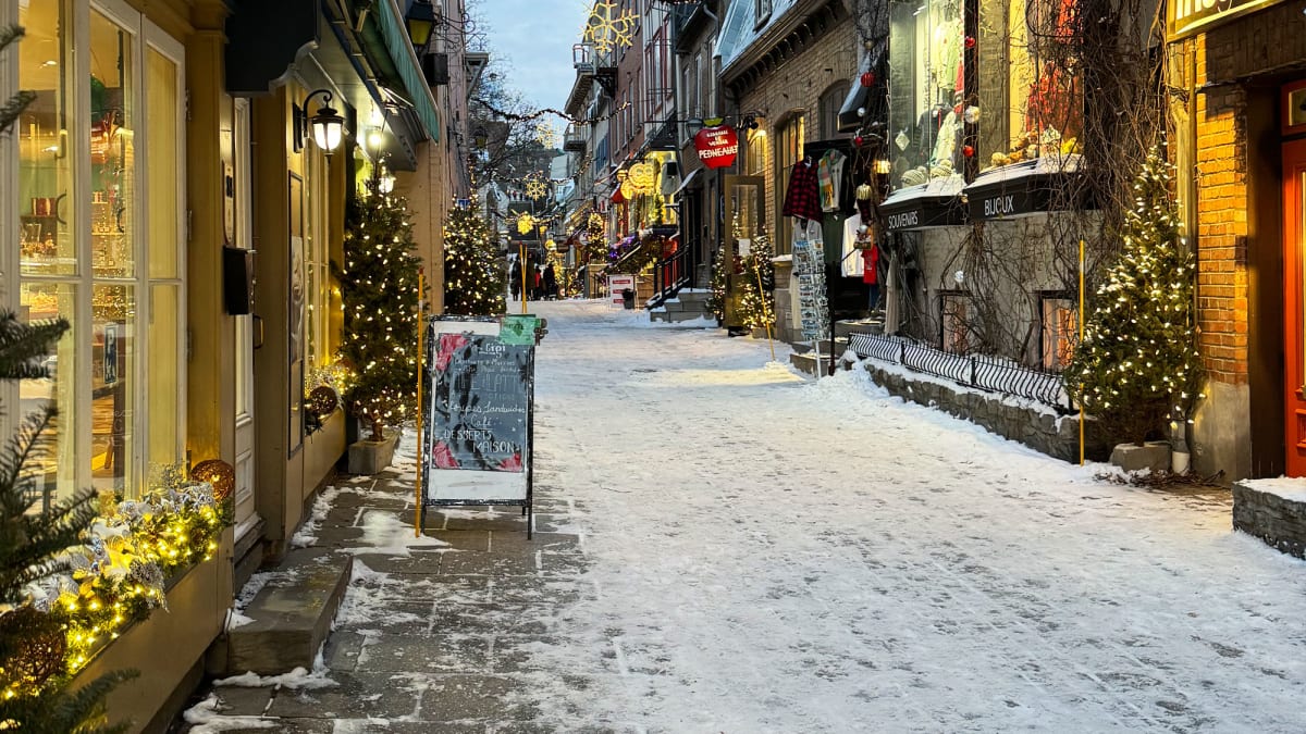 A snow-covered pedestrian street in Old Québec lined with shops.