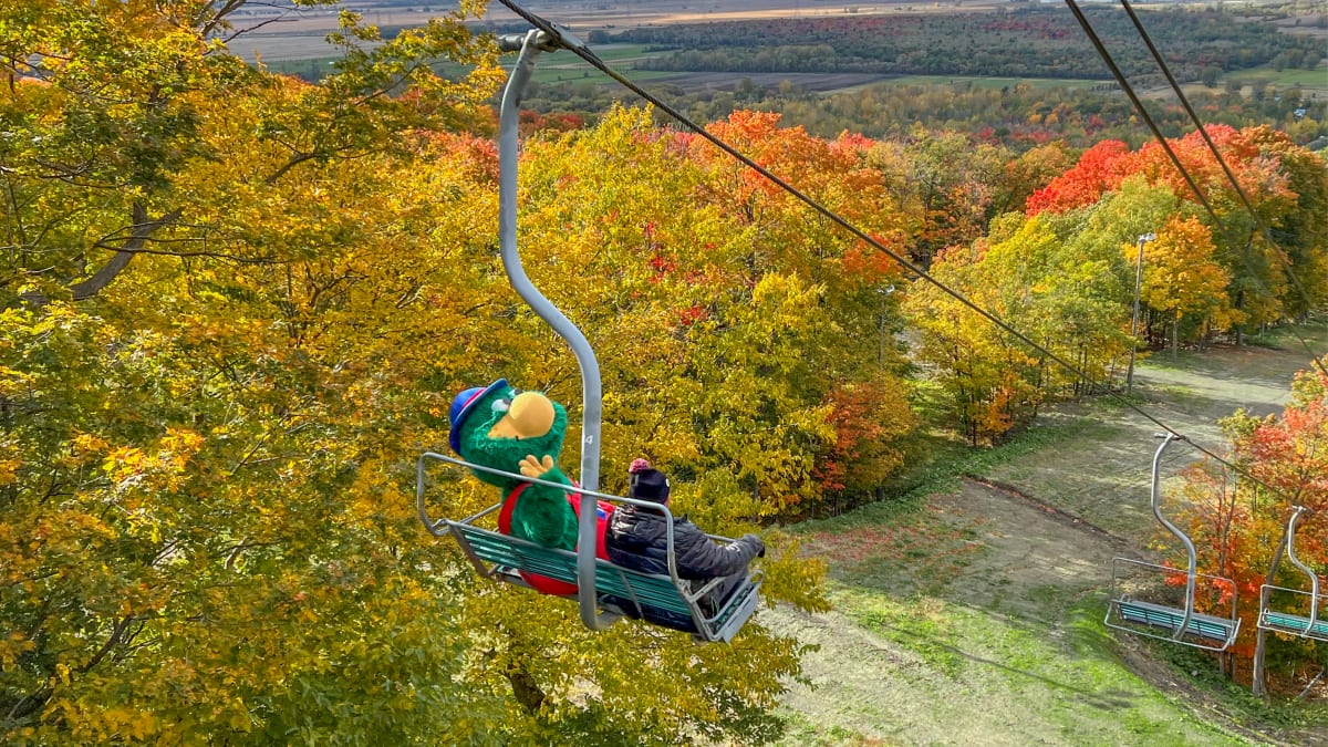 Mascot and boy on a ski lift in the fall.