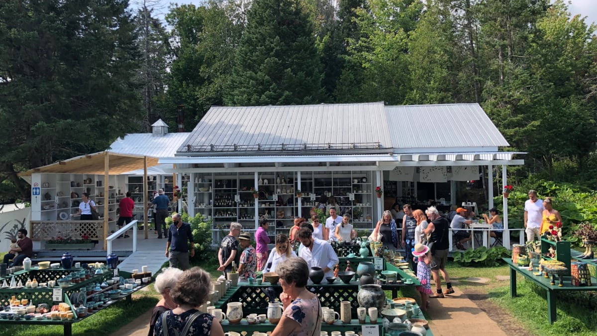 The exhibition site, with a small house and outdoor tables filled with ceramics.