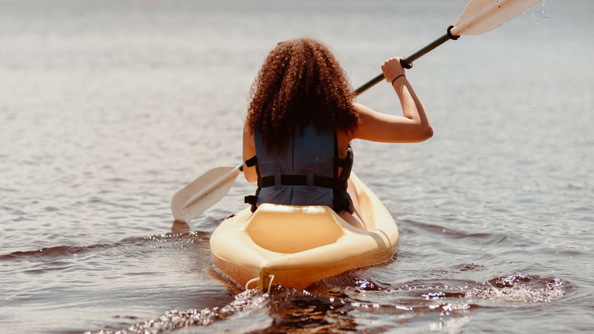 Jeune femme en kayak sur le lac. Young woman in a kayak on the lake.
