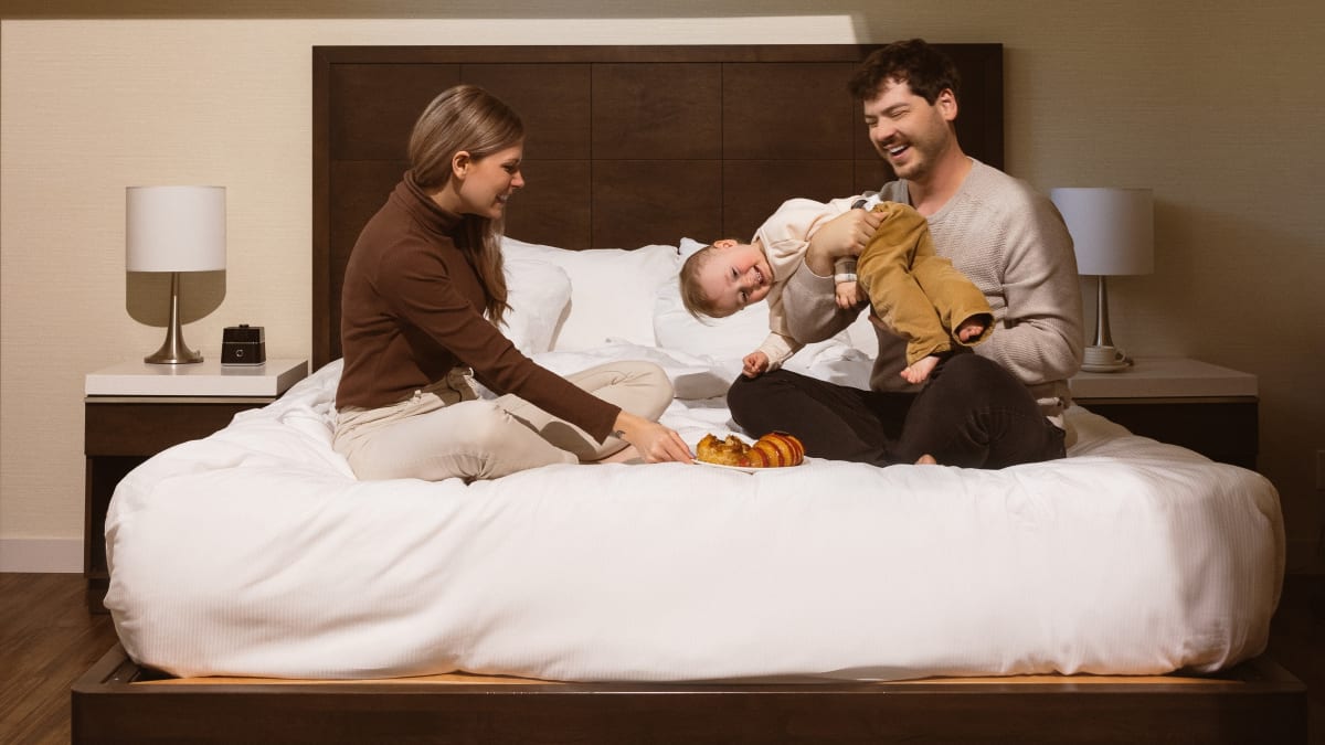 Two young parents and a child on a bed.