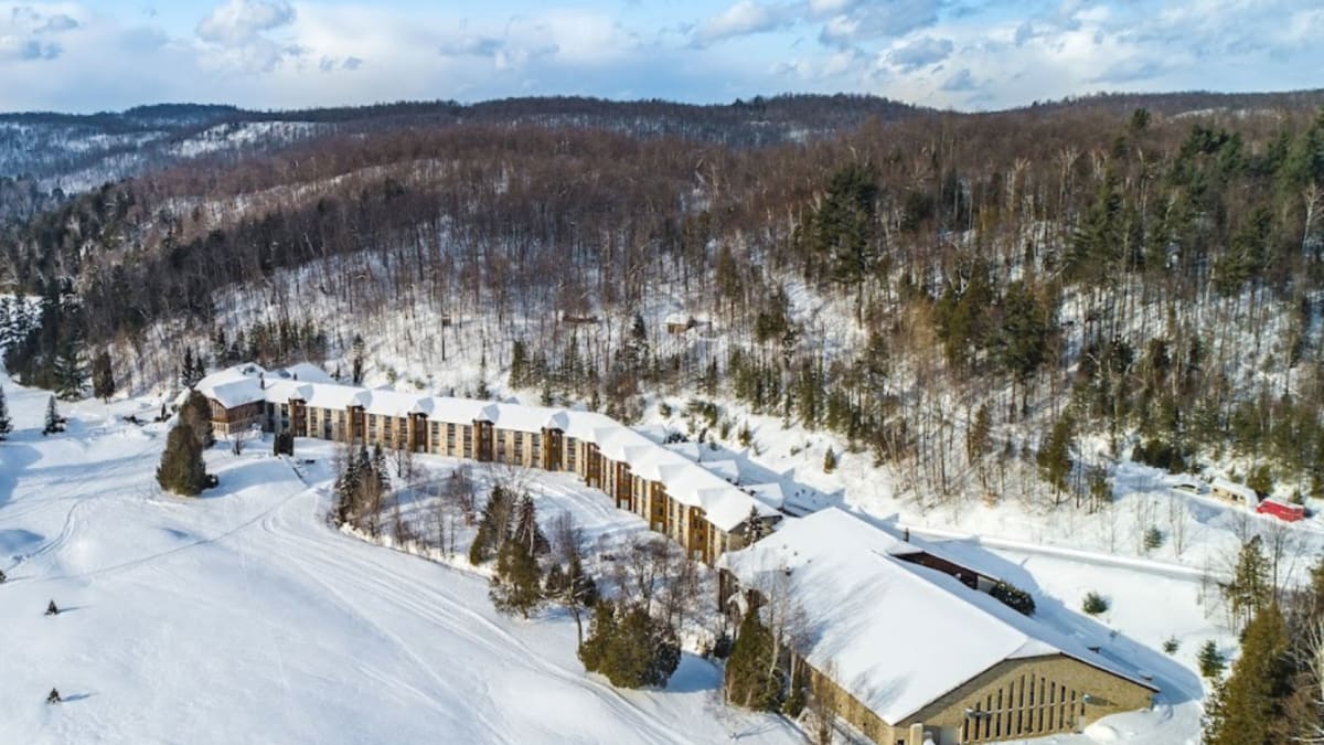 Vue aérienne de l’hôtel, entouré d’étendues enneigées et d’arbres dénués de leur feuillage.