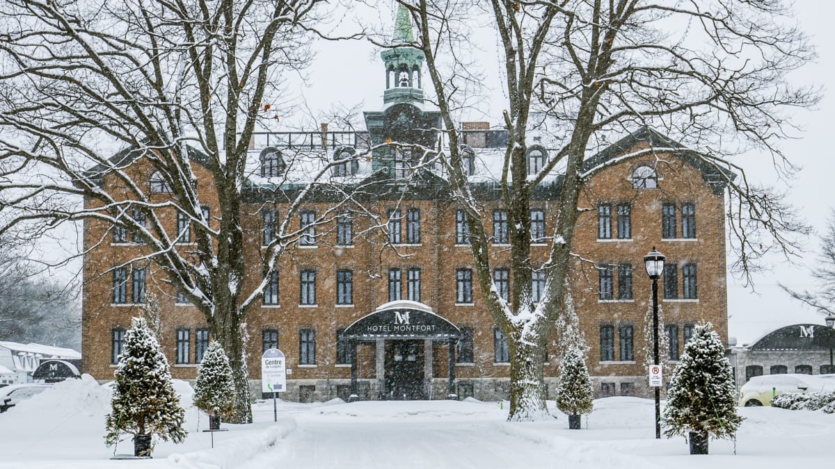 Devanture de l'Hôtel Montfort, un bâtiment d'allure historique de 4 étages, sous la neige.