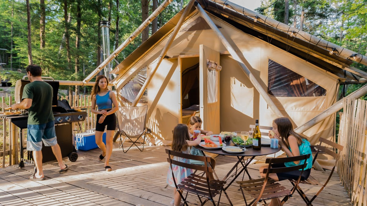 Family of four enjoying the sunshine on the terrace of their ready-to-camp tent.