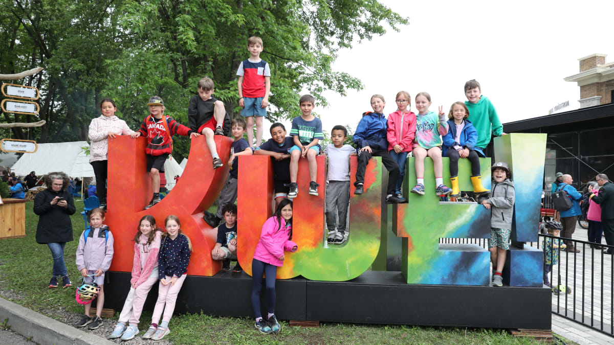 Enfants autour du logo géant du festival KWE.