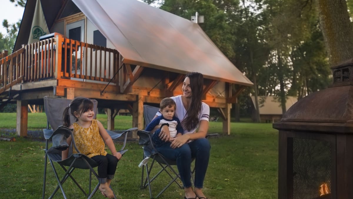 Mère et ses deux enfants au bord du feu de camp devant un prêt-à-camper