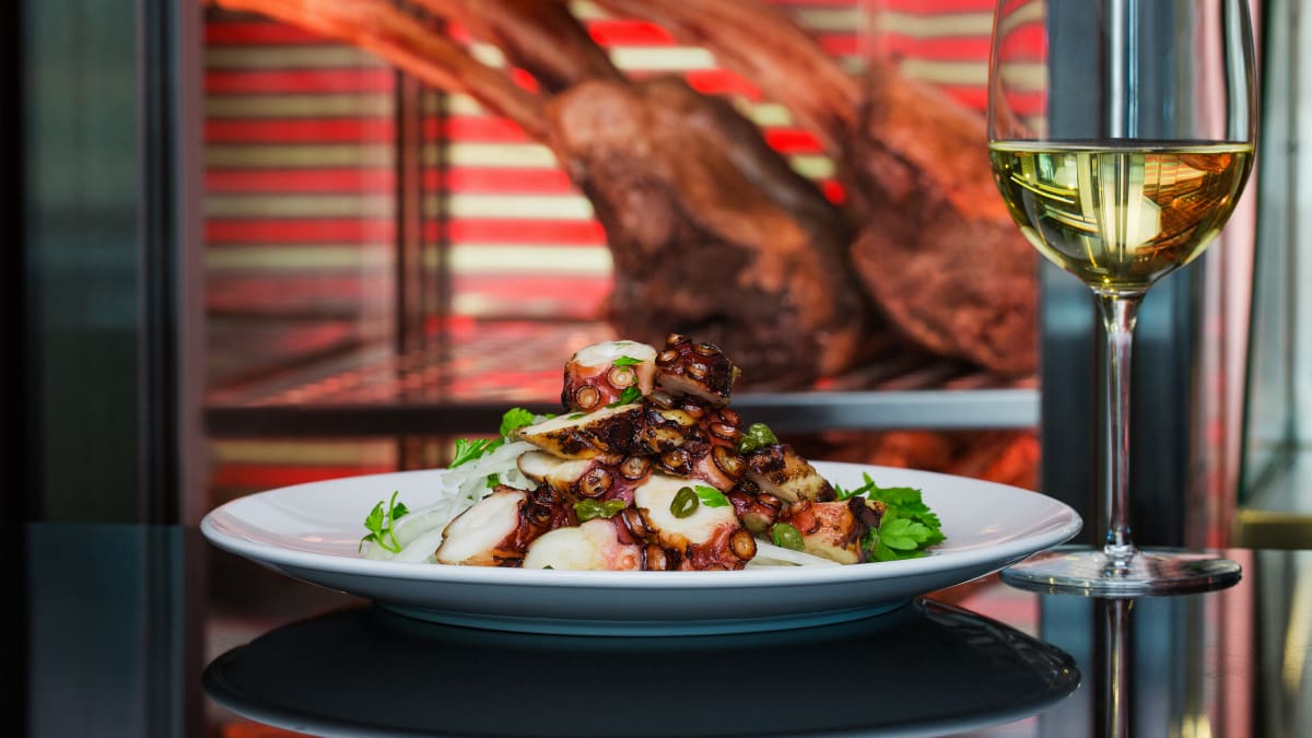 A plate of carefully prepared seafood, served with a glass of white wine.