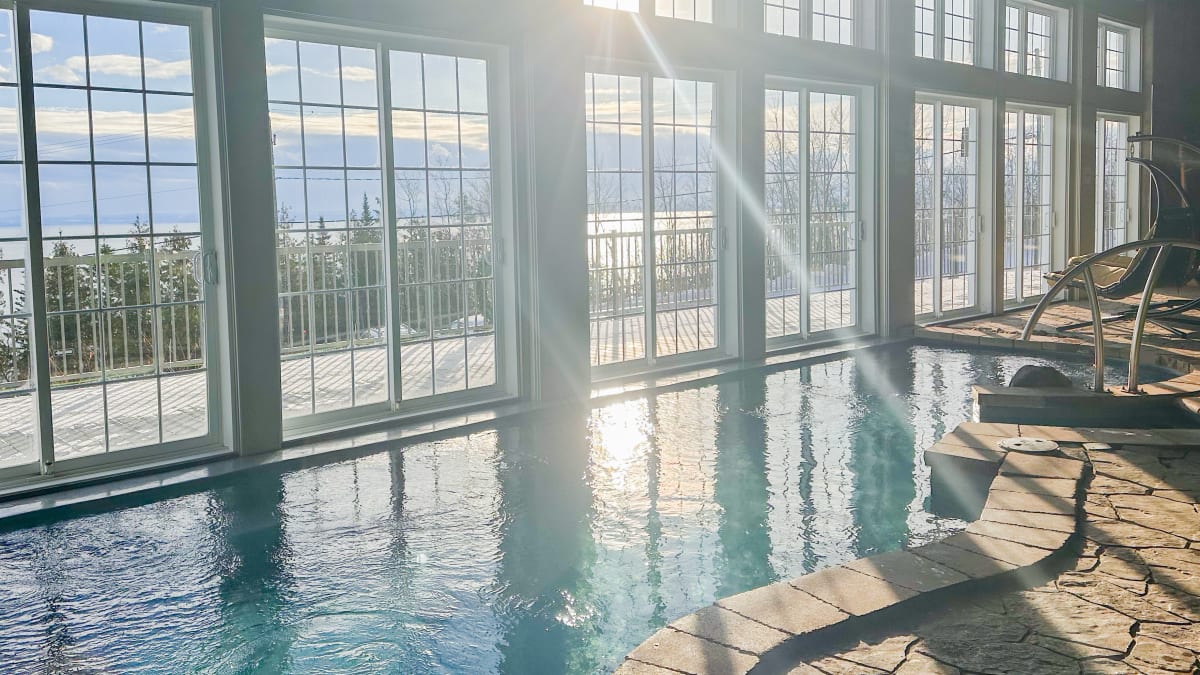 Piscine intérieure dans un spa à côté de baies vitrées.