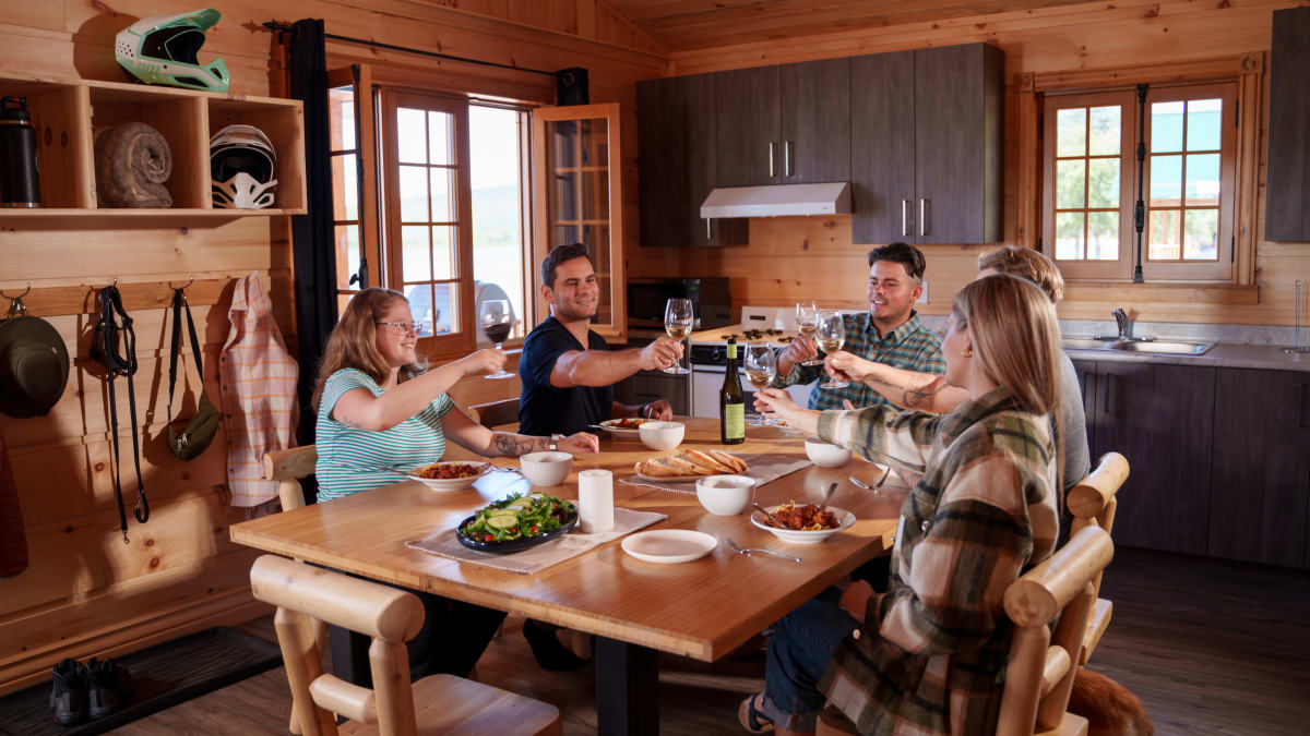 Group of diners around a table inside a wooden cottage.