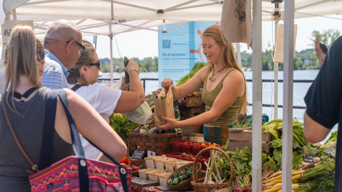 Booth at the farmer's market with customers lined up and merchant.