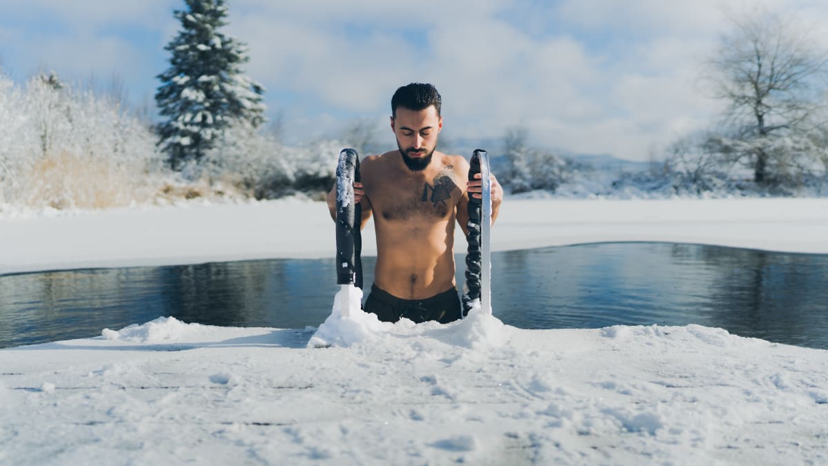 A man emerging from a pool of water surrounded by snow.