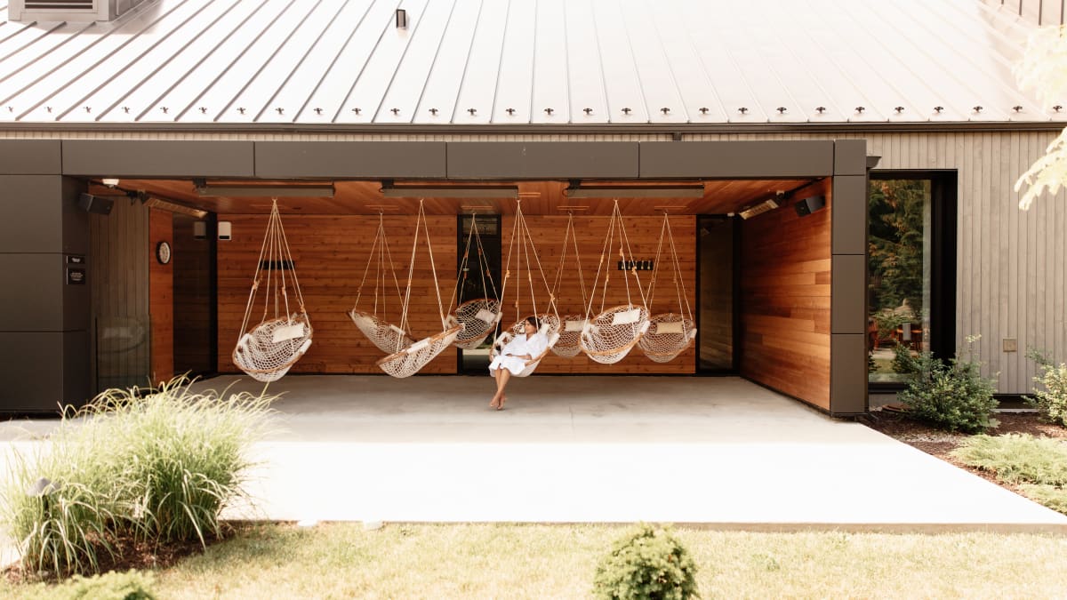 Woman in an outdoor relaxation area, equipped with hanging seats.