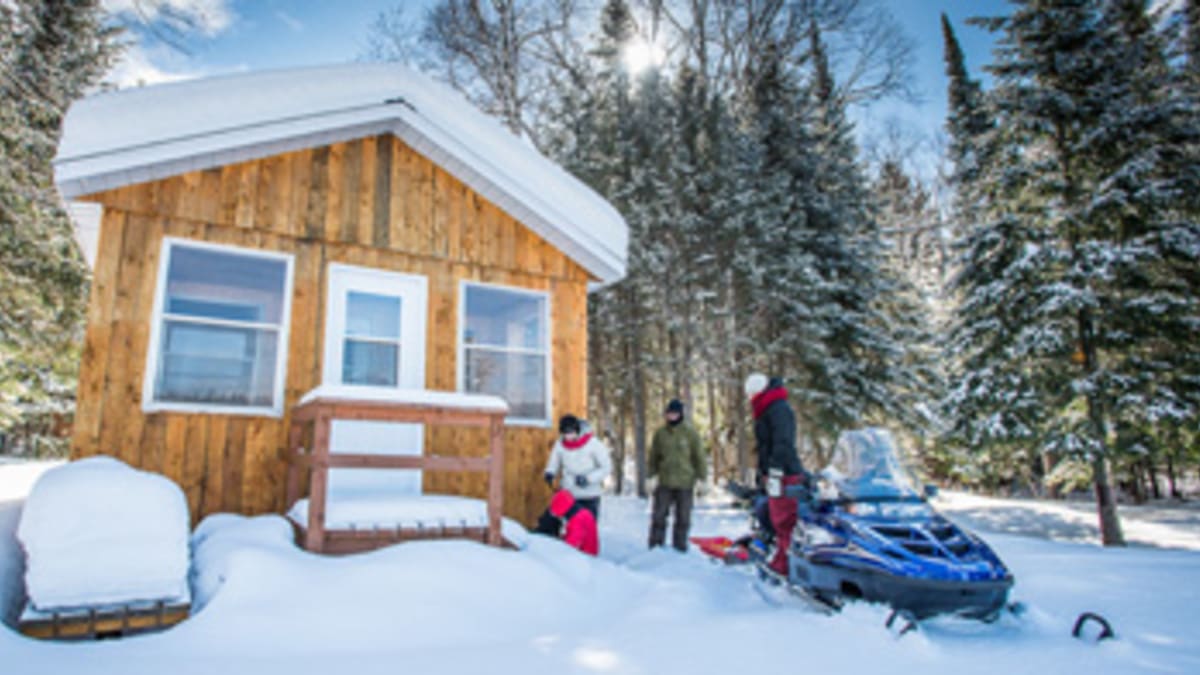 Chalet en hiver avec motoneigiste
