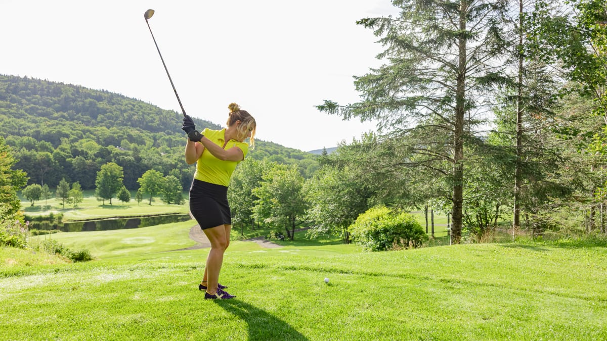Woman on a golf course about to hit the ball.