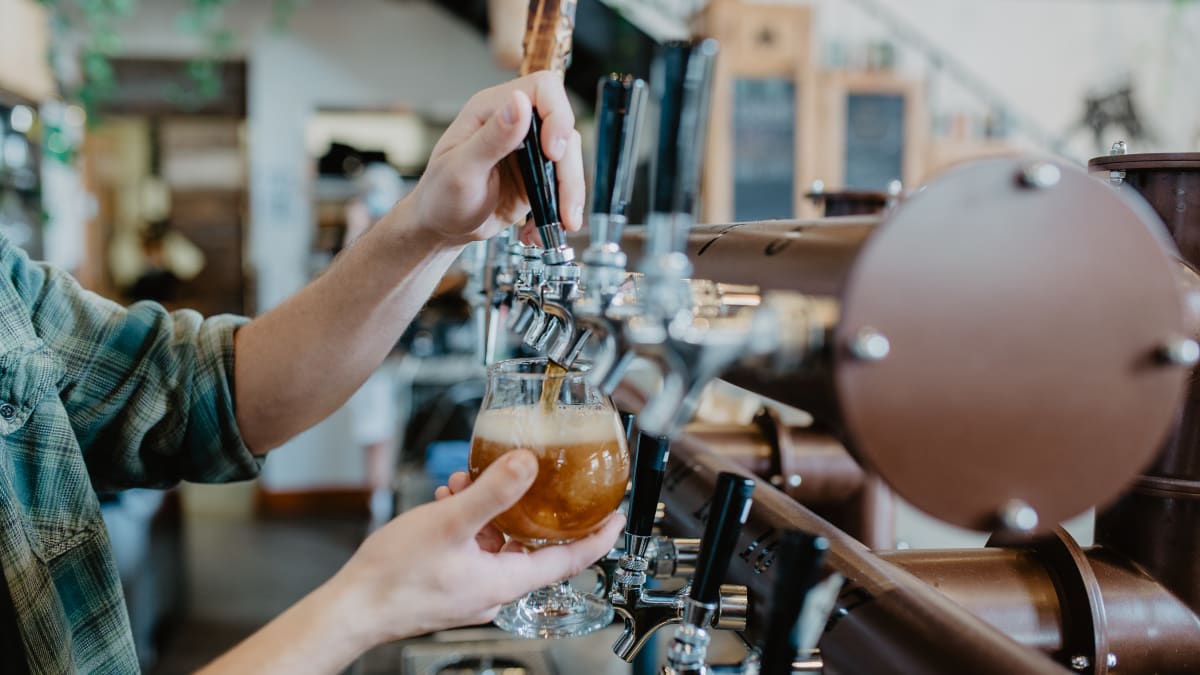Un barman rempli un verre de bière à la pression.