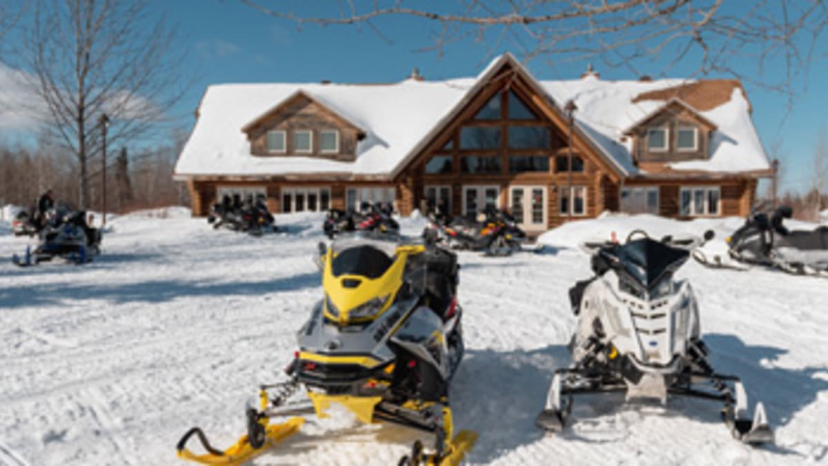 Two snowmobiles in front of a lodge