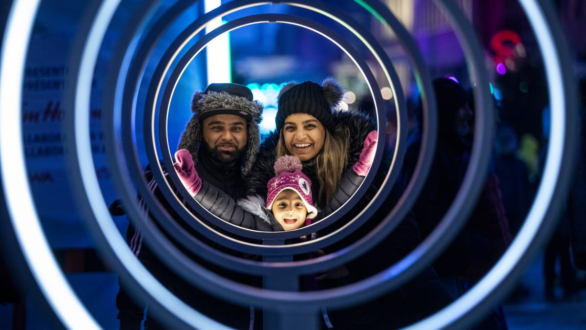 Smiling father, mother and little girl admiring a luminous installation at Winterlude.