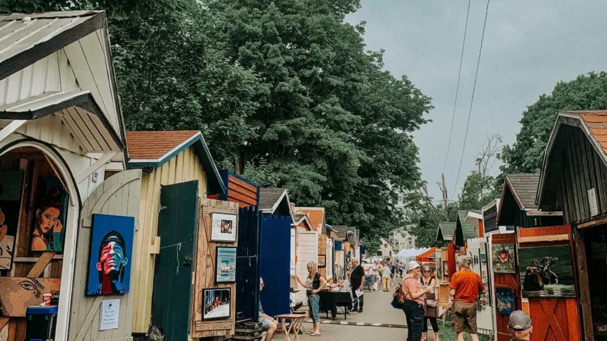 Ruelle bordée de petites cabanes dans lesquelles sont exposées des oeuvres d'art.