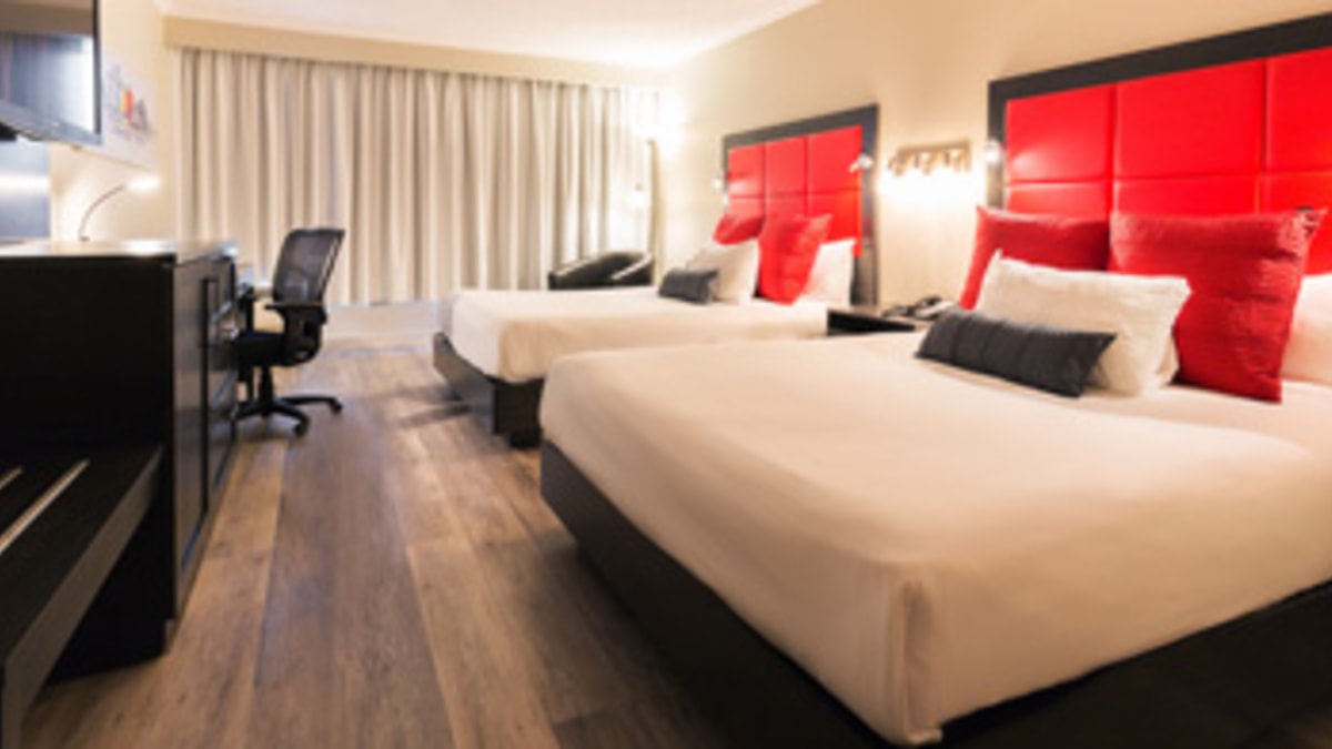 Interior of a red-accented hotel room with two queen-size beds