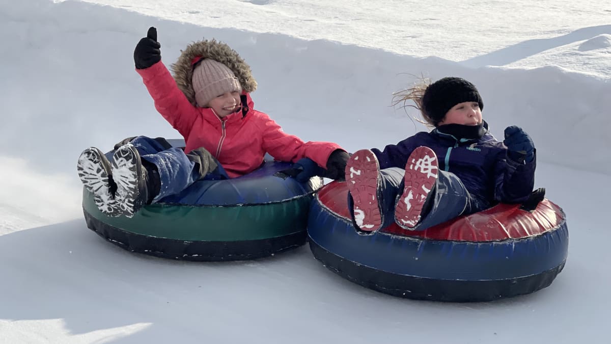 Two children sliding down on tubes.